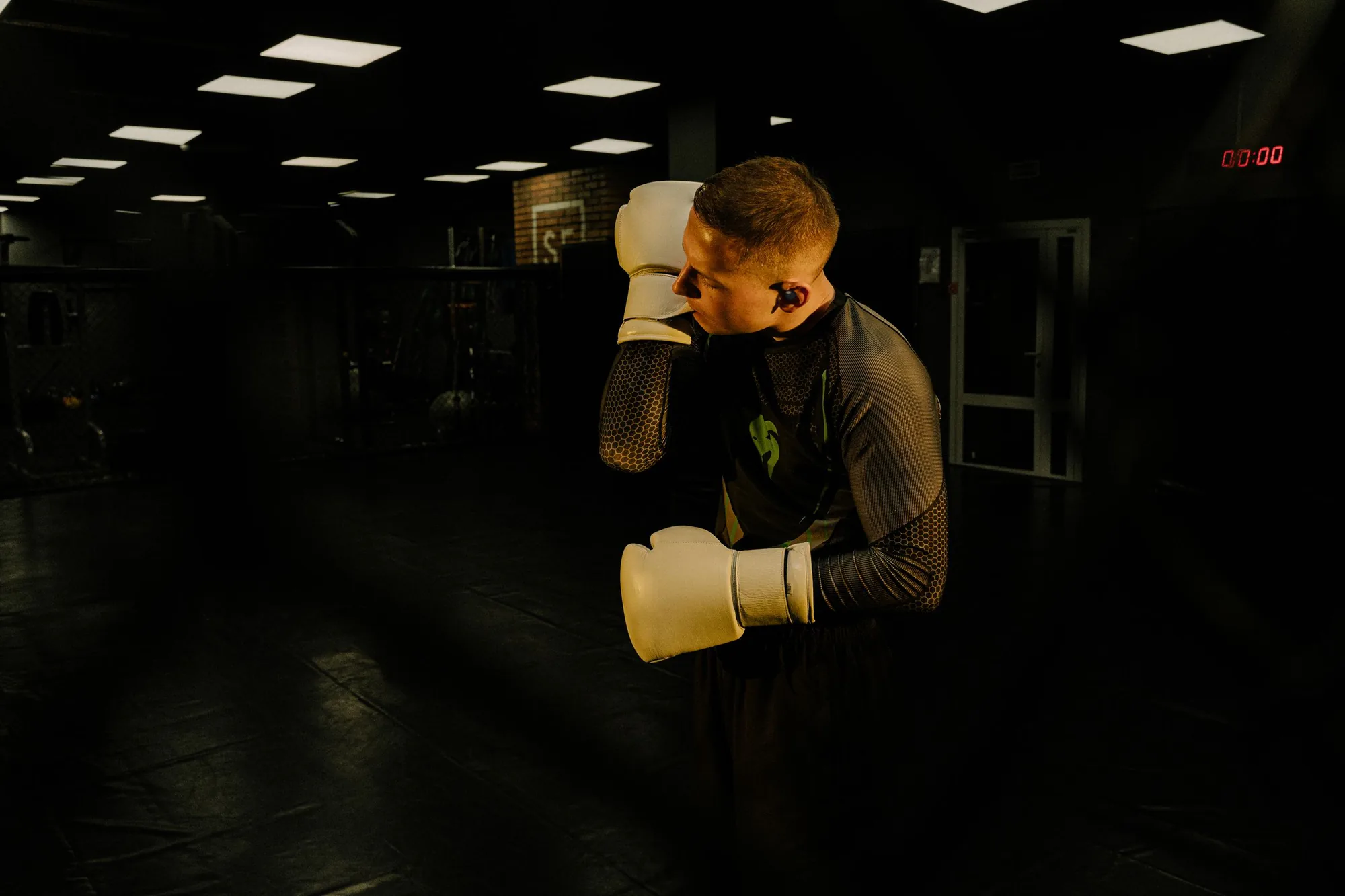 Boxer training with a wireless earbud in a dark gym