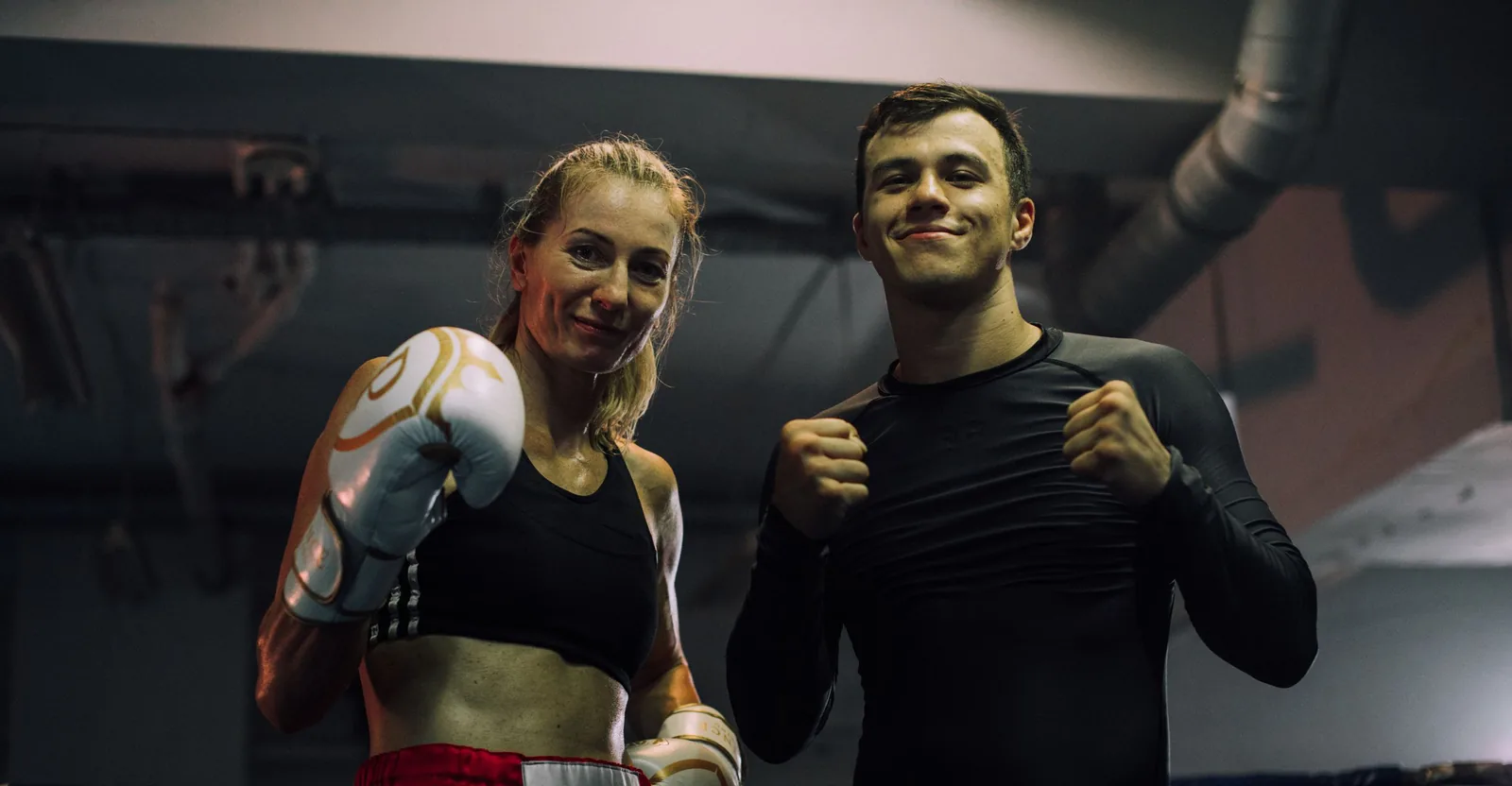 Two training partners smiling in a boxing gym